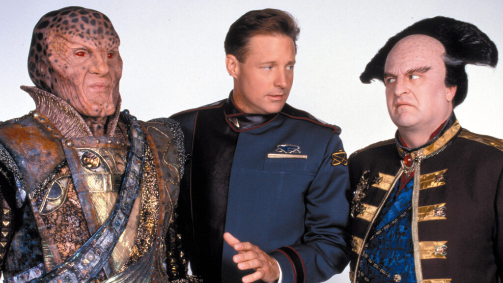 An image of G'kar, Captain Sheridan, and Londo Mollari.

G'kar is a humaniod alien with a patterned bald head and red eyes, Sheridan is a human of average Caucasian variety, and Londo looks like an aging human with striking hair that forms a crescent halfway across his head. All are wearing formal uniforms of very different varieties.