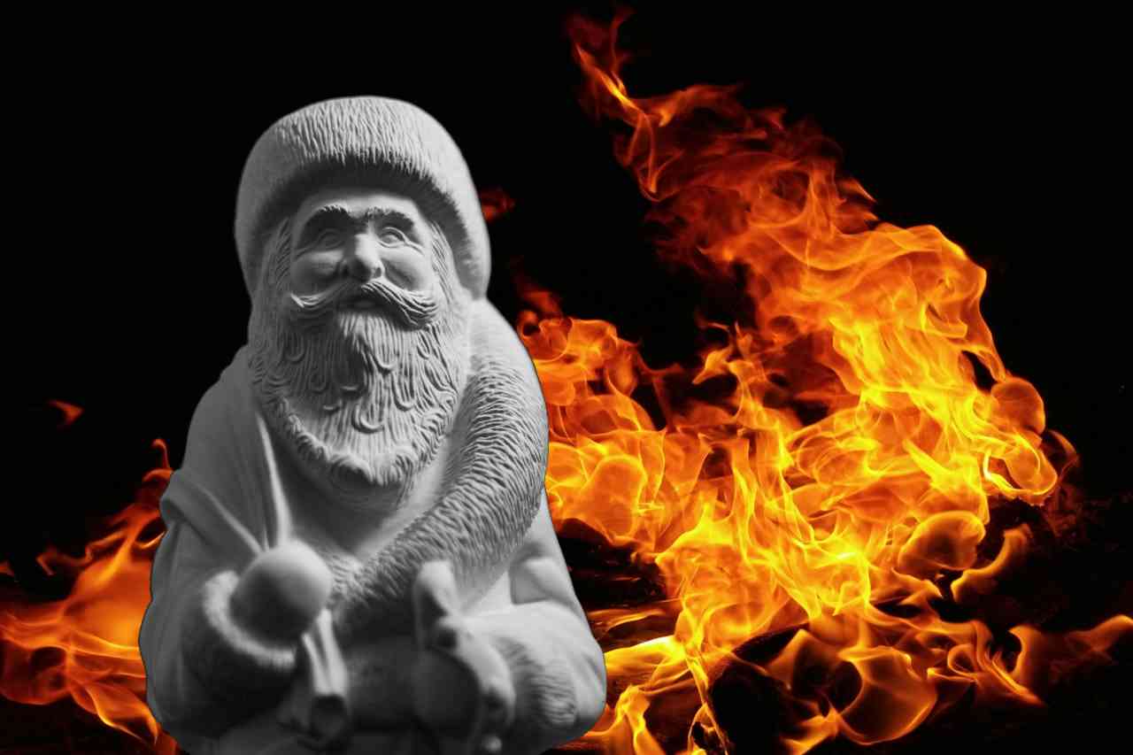 A stone figure of Santa against a background of fire and blackness