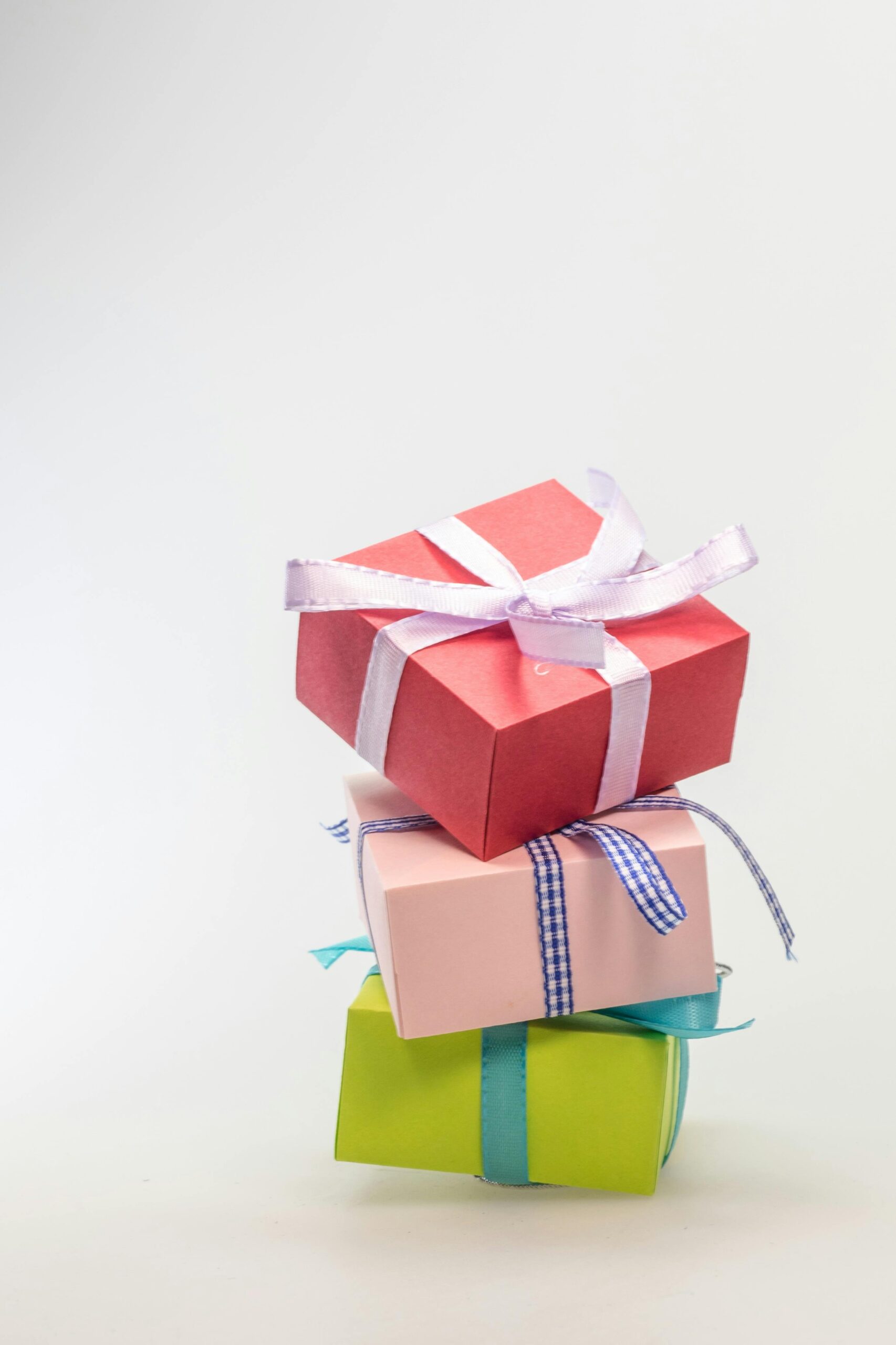 A stack of three small gifts in pastel colors against a white background